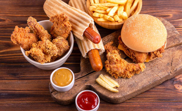 Delicious but unhealthy food with ketchup and mustard on vintage cutting board. Fast carbohydrates, junk and fast food. Warm wooden background.