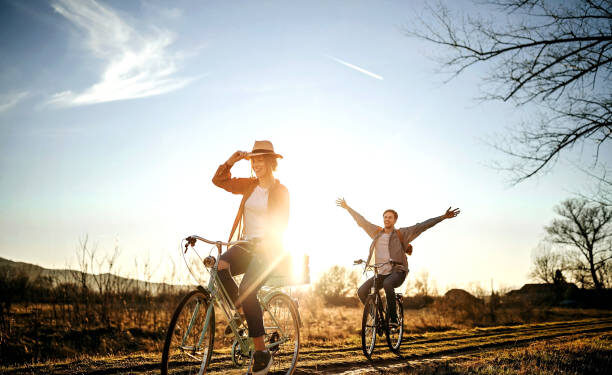 Couple driving on bicycle in nature, enjoying the sun