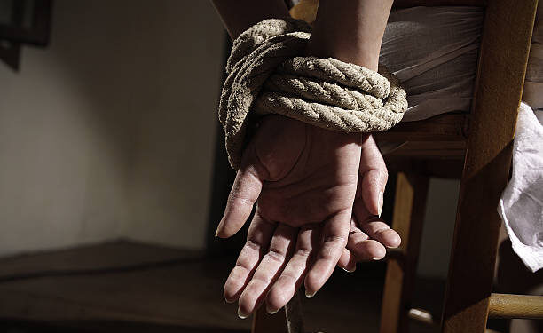 Young woman tied to a chair in a empty room, hands close up