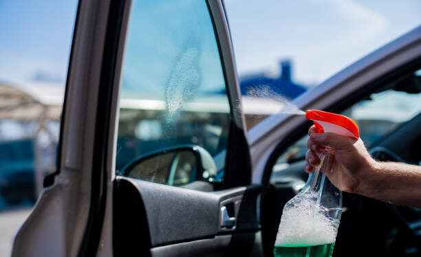 self-service car wash. a man washes the car window with glass cleaning liquid. professional cleaning of transport. car washer.