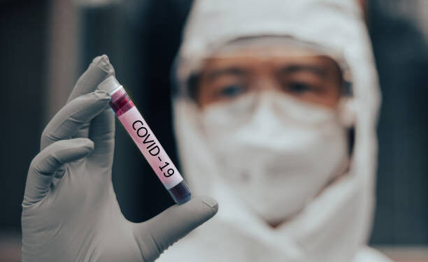 COVID-19 named by WHO for Novel coronavirus NCP concept. Doctor or lab technician in PPE suit holding blood sample with novel (new) coronavirus in Wuhan, Hubei Province, China, medical and healthcare