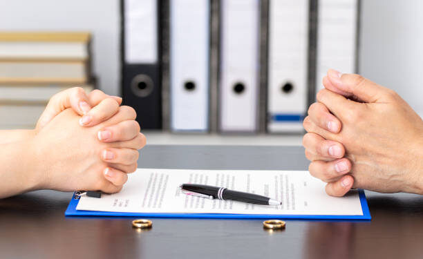 Hands of wife and husband signing divorce documents or premarital agreement at the lawyer's office