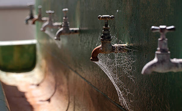 An old rusted wash trough and taps at Fremantle Prison, Australia, complete with cobwebs