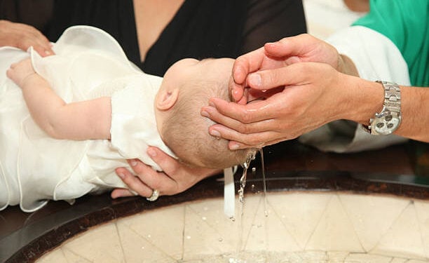 Newborn baby baptism by water with hands of priest