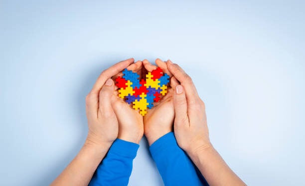 World autism awareness day concept. Adult and child hands holding puzzle heart on light blue background. Top view.