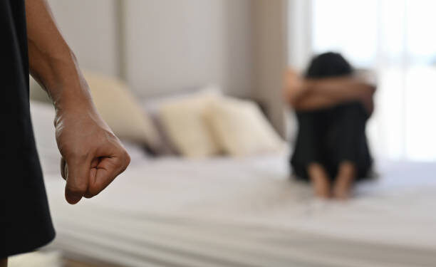 Selective focus on the fist male with crying man sits on a bed as the background, Violence, Love and relationships, Gay couple, sexual harassment concept.