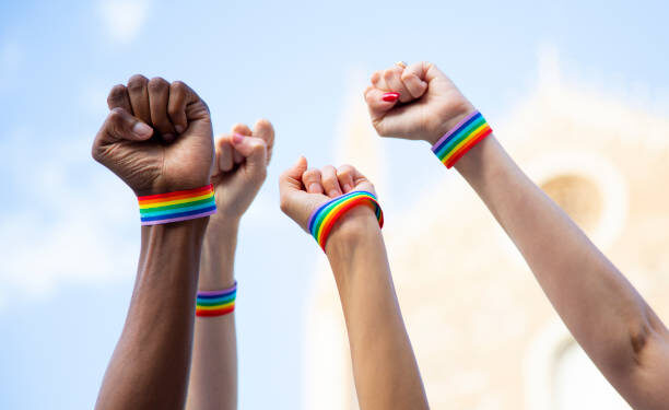 Four fists claiming gay pride rights with gay pride bracelet. LGBT and equal rights concept