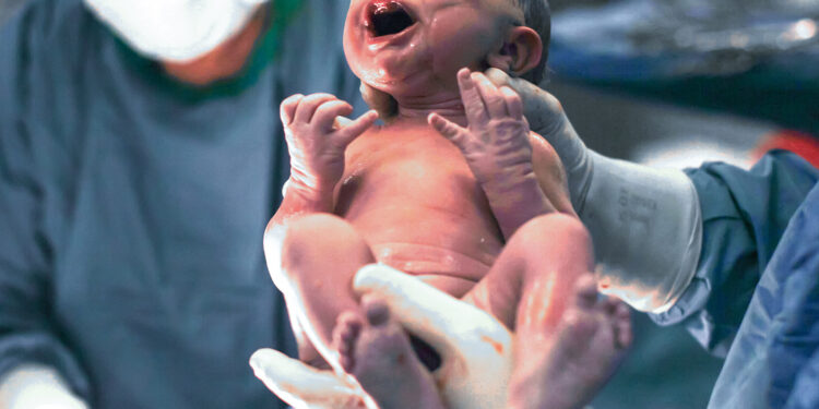 Doctors holding newborn baby boy.