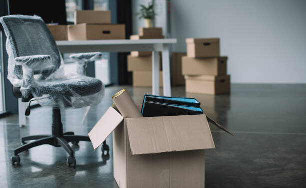 cardboard box with folders and office supplies in floor during relocation