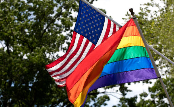 Rainbow and American flags in the wind flying proudly together. Image shot with Canon 5D Mark 4, EF 70-200mm f/2.8L lens.