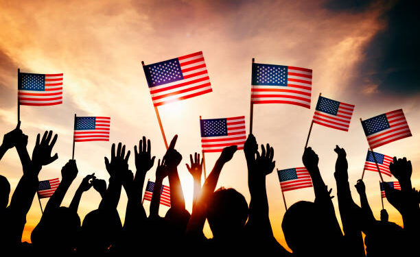 Group of People Waving American Flags in Back Lit