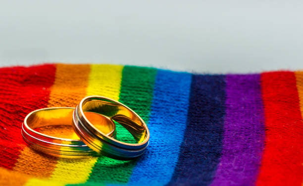 Two wedding rings on the fabric colors of the rainbow. Concept same-sex marriage.