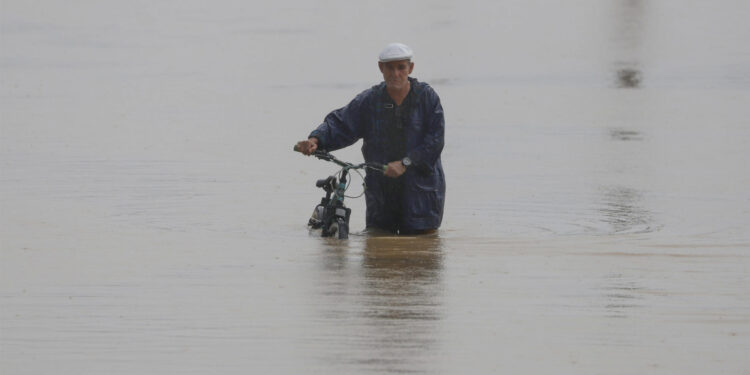 Un hombre cruza con su bicicleta una calle inundada debido a las intensas lluvias en Toa Baja (Puerto Rico). Imagen de archivo. EFE/Thais LLorca