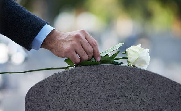 Cropped shot of a man placing a white rose on a grave