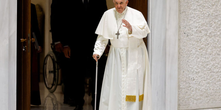 El Papa Francisco saluda a los visitantes mientras entra caminando con la ayuda de su bastón en el Aula de Audiencias Pablo VI para comenzar su audiencia general en el Vaticano el 23 de agosto de 2023. (Foto CNS/Lola Gomez)