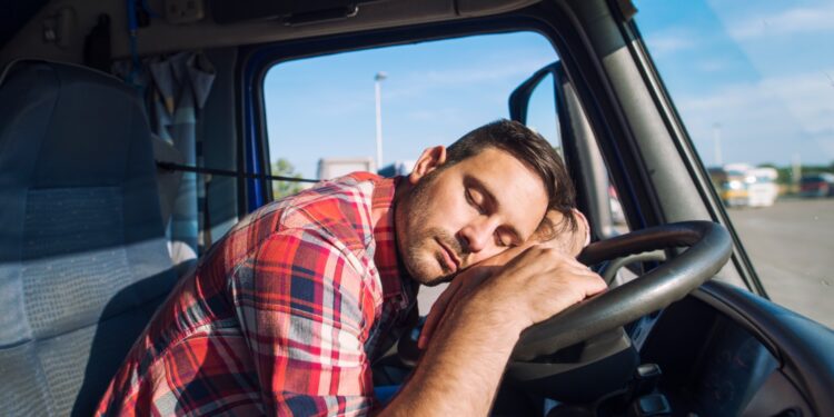 Exhausted truck driver falling asleep on steering wheel.