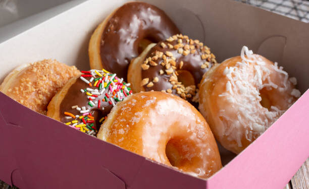 A view of a pink box filled with a half dozen favorite donut varieties.