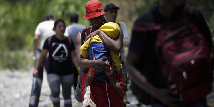 Una persona migrante haitiana carga a su hijo en la selva mientras esperan para ser trasladados en canoa desde la Quebrada León hasta a la comunidad de Bajo Chiquito en Darién (Panamá). EFE/ Bienvenido Velasco