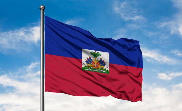 Flag of Haiti waving in the wind against white cloudy blue sky. Haitian flag.